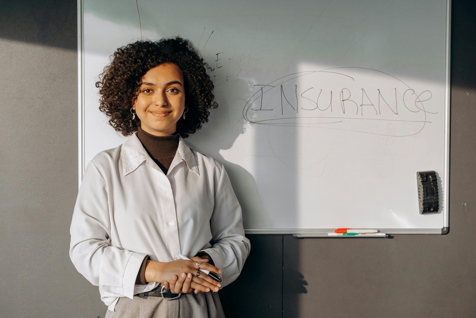 Smiling woman standing in front of a whiteboard with the word 'Insurance' written on it